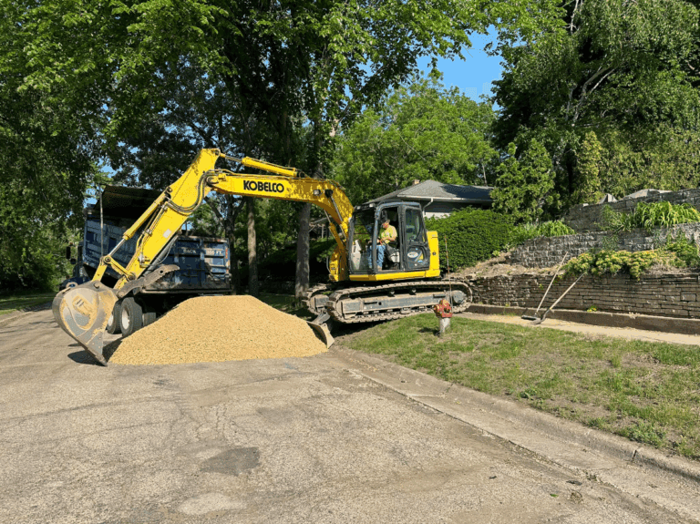 Spreading landscaping gravel with excavator